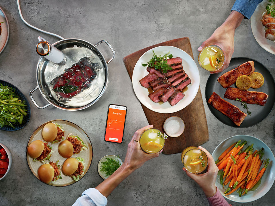 Table with dishes, Joule Turbo Sous Vide and phone displaying Autopilot on the screen