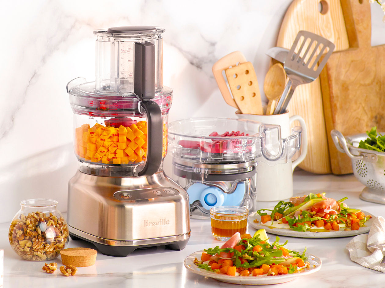 Breville Kitchen Wizz 9 cup compact food processor sitting on a kitchen bench with colour-coded accessories.