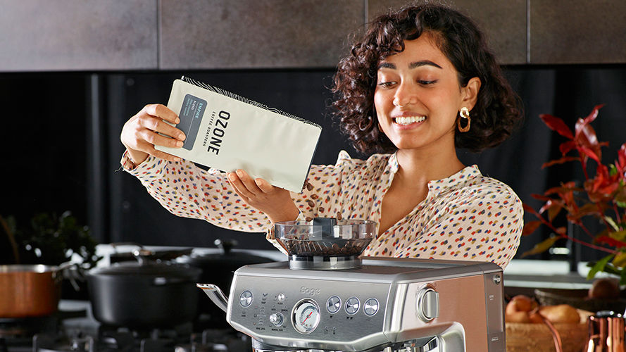 woman putting coffee beans in espresso machine