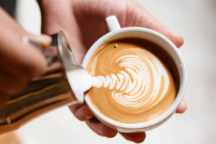 Barista creating beautiful latte art in coffee cup