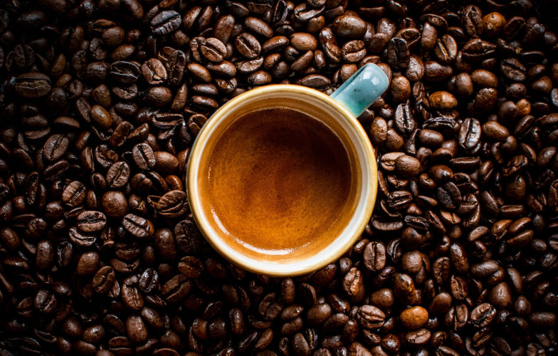 Flat lay of coffee cup with roasted beans surrounding