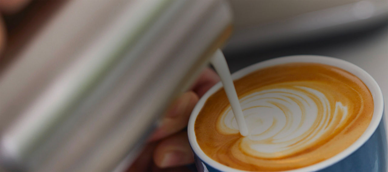 Milk being poured into cup to create latte art 